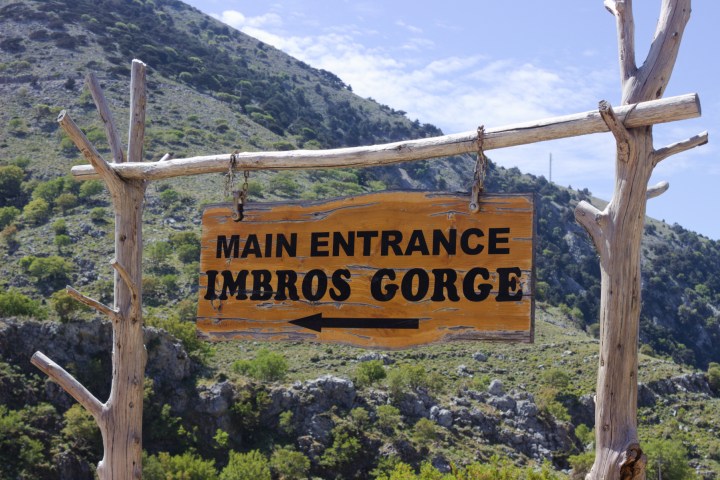 a wooden sign with a mountain in the background